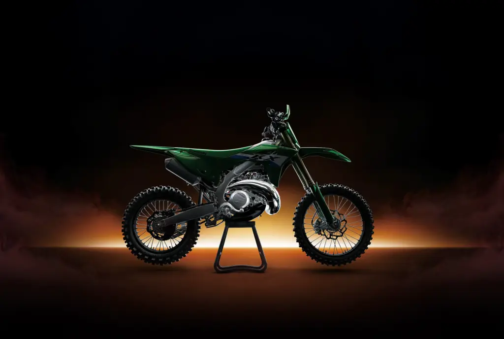 Kawasaki KX motocross bike in green on a stand, lit against a dark background